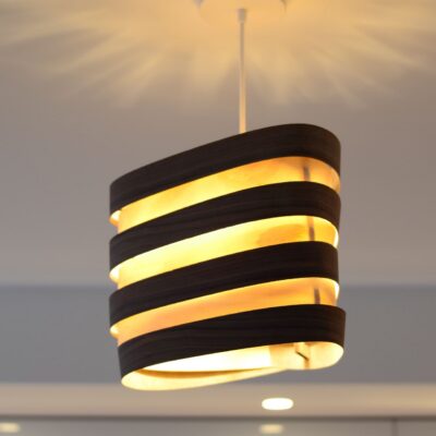 Suspensions Nest Duo en bois de bouleau et noyer installées au-dessus d’un îlot de cuisine moderne, lumière douce et naturelle.